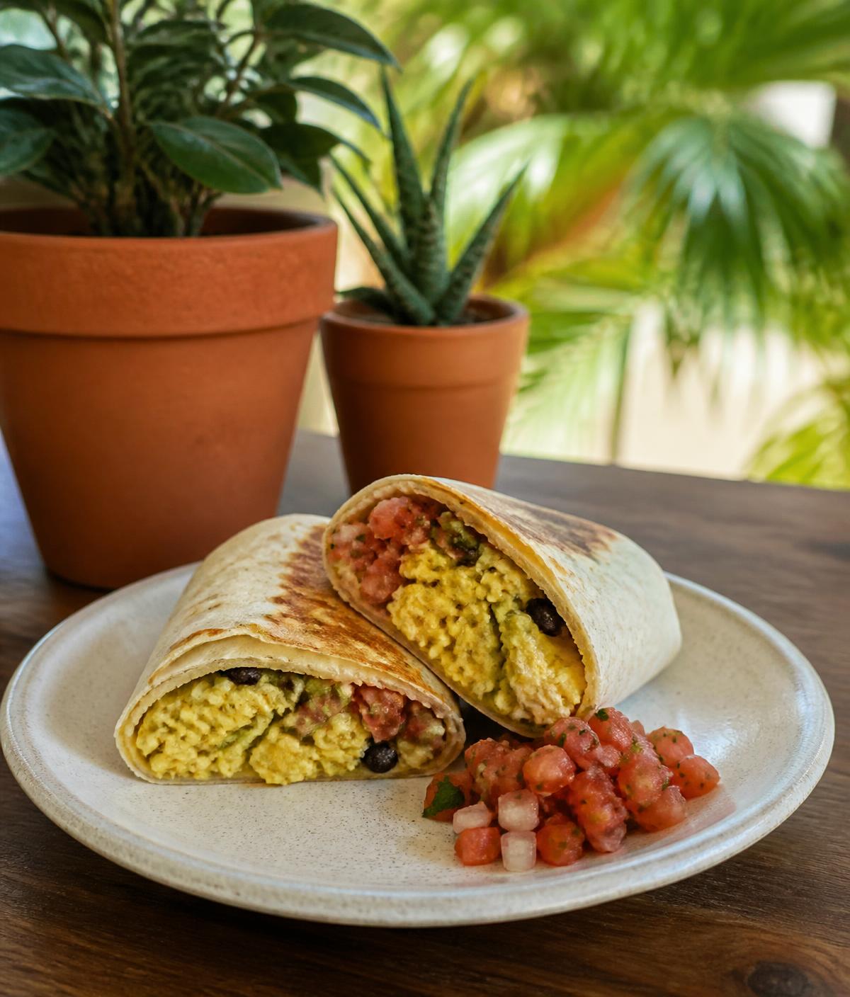 Breakfast burrito sliced open with scrambled eggs and fresh salsa